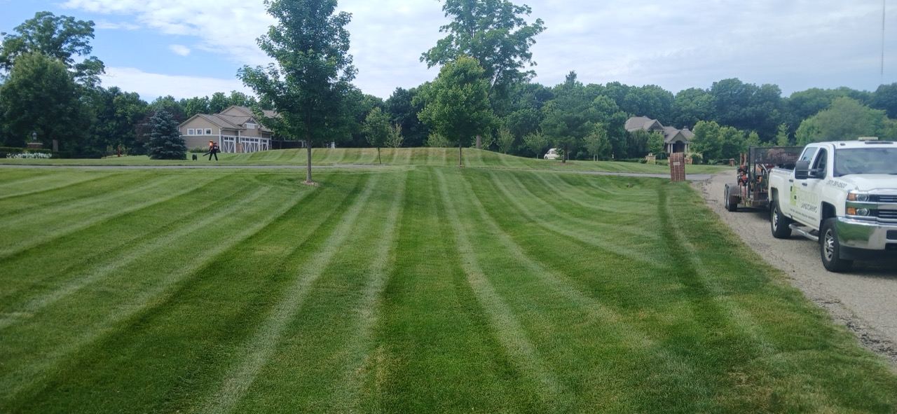 Large striped front lawn on a cul-de-sac lot with our service truck and trailer on site