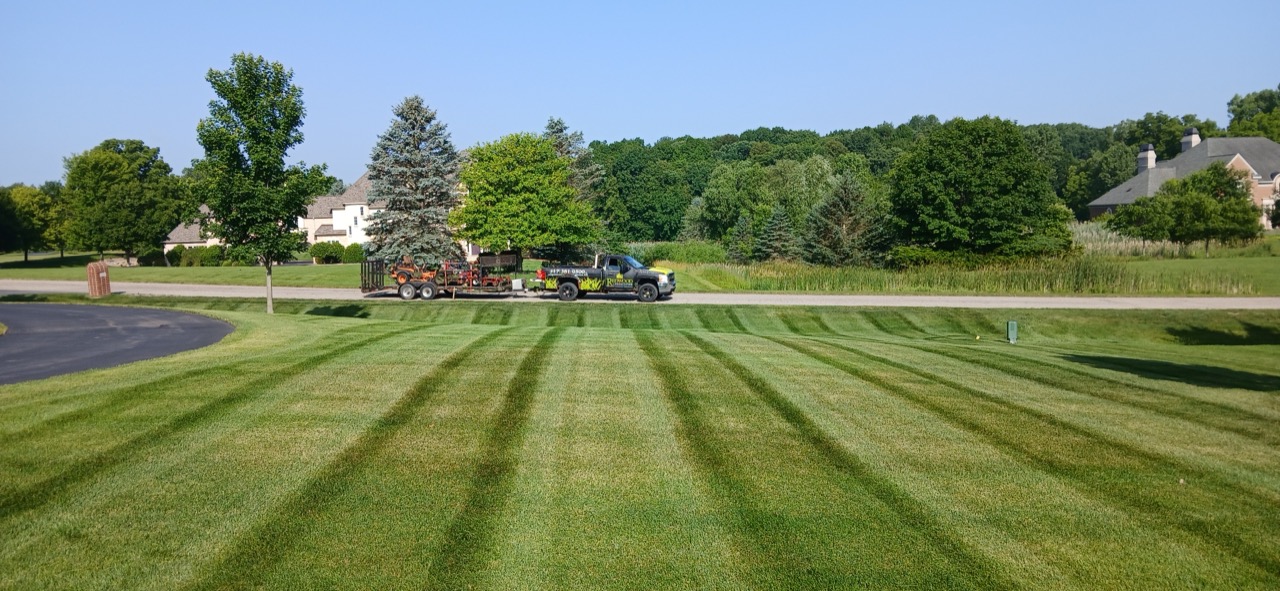 Redwood Landscaping truck and trailer parked beside a freshly striped estate lawn